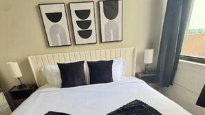 A hotel room with a large bed, a headboard, two bedside tables with lamps, and three wall-mounted artworks. - Chic Serenity Loft / Fast Wi-Fi Walkable (Cleveland)