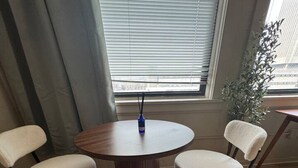 A round wooden table with a blue vase in the center, flanked by two upholstered chairs with black legs. - Chic Serenity Loft / Fast Wi-Fi Walkable (Cleveland)