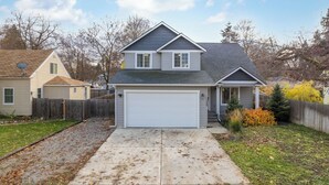 A single-story house with a garage, a front yard with a small tree, and a wooden fence.