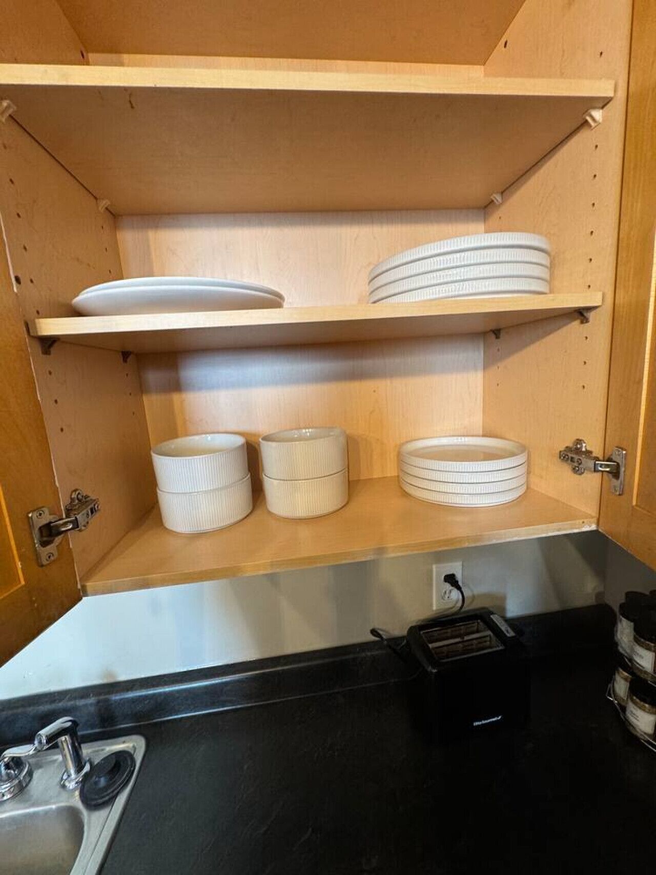 Cucina con pensili in legno, un piano di lavoro nero e un lavello.