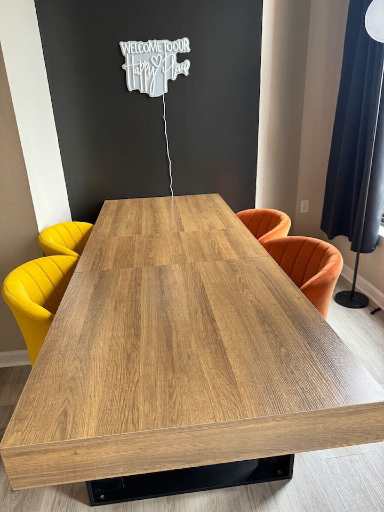 Un comedor moderno con una mesa de madera y dos sillas, una amarilla y otra naranja.