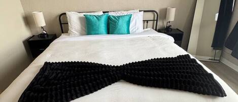 Habitación de hotel con cama, dos mesitas de noche, un espejo y tres cuadros colgados en la pared.