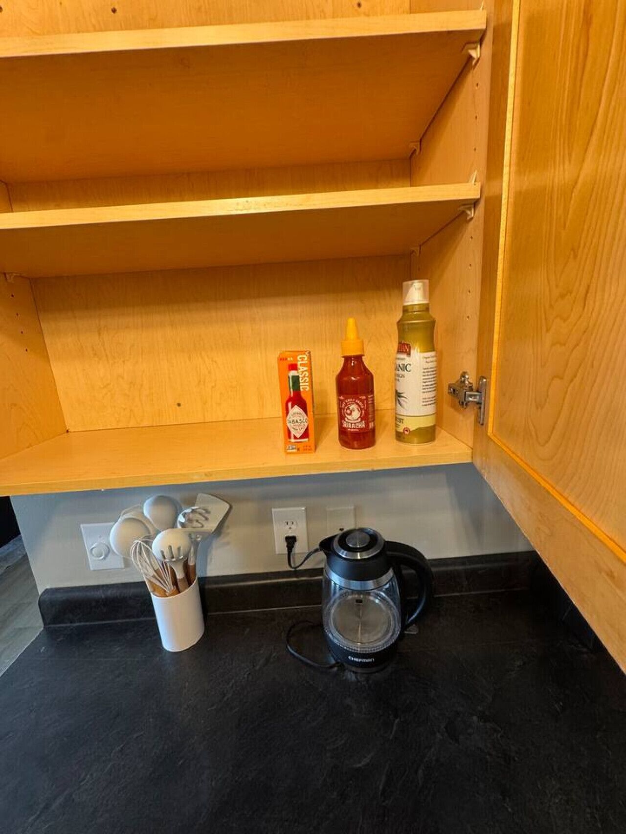 Una cocina con un mueble de madera, una cafetera y condimentos sobre la encimera.