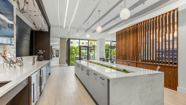 A modern kitchen with a marble island, wooden accents, and pendant lighting. - Hyatus Curated Residences Everett (Everett)
