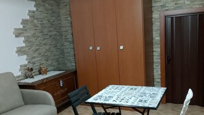 A room with a sofa, a dining table with chairs, a wardrobe, and a decorative wall. - Studio apartment in the historic center renovated (Pietragalla)