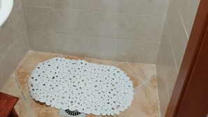 A shower area with a white shower curtain, a showerhead, and a white circular mat on the floor. - Studio apartment in the historic center renovated (Pietragalla)