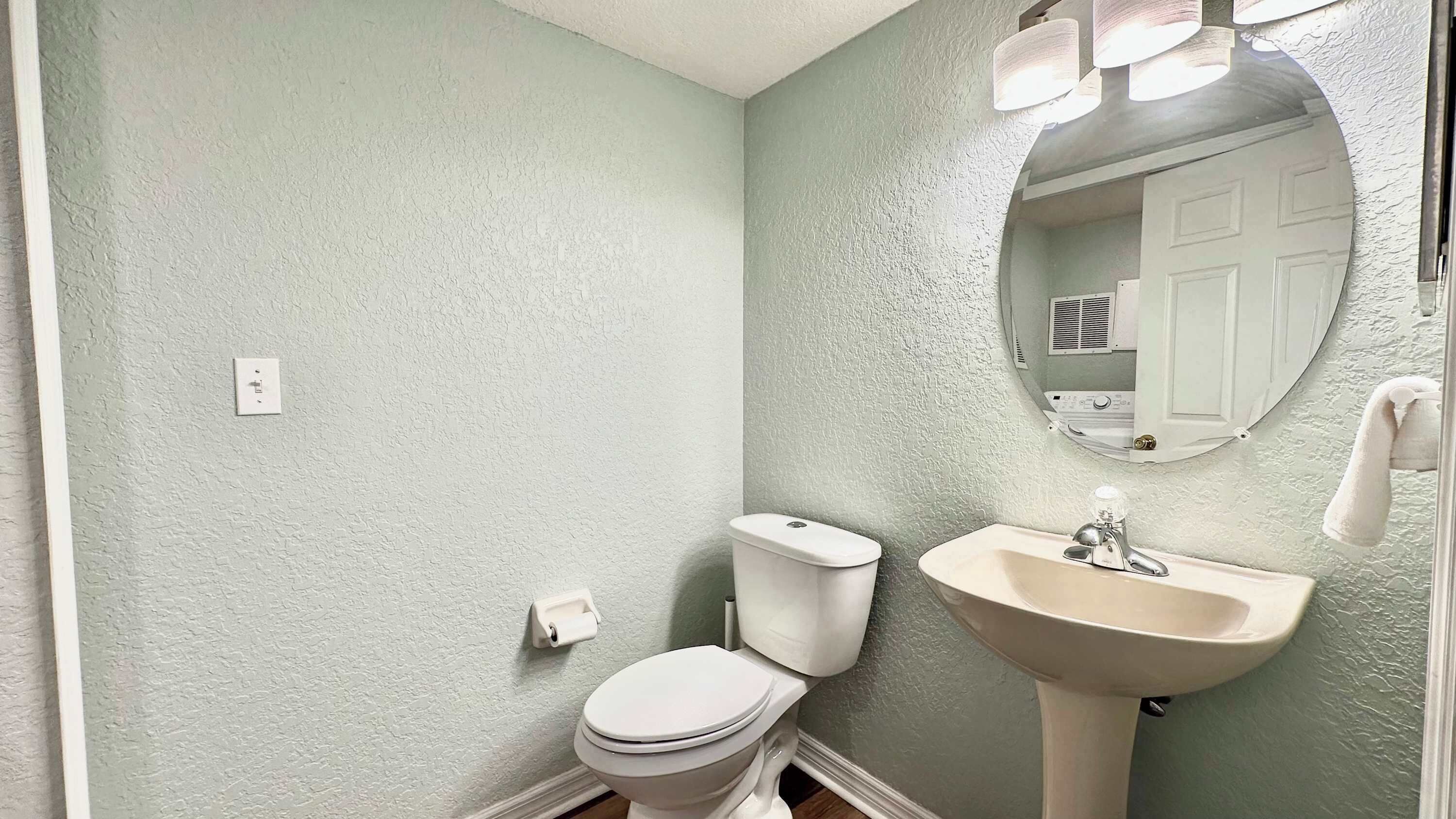 A bathroom with a toilet, sink, and mirror.