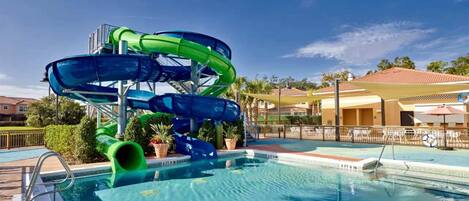 A pool with a water slide structure, a pool deck, and a clear sky.