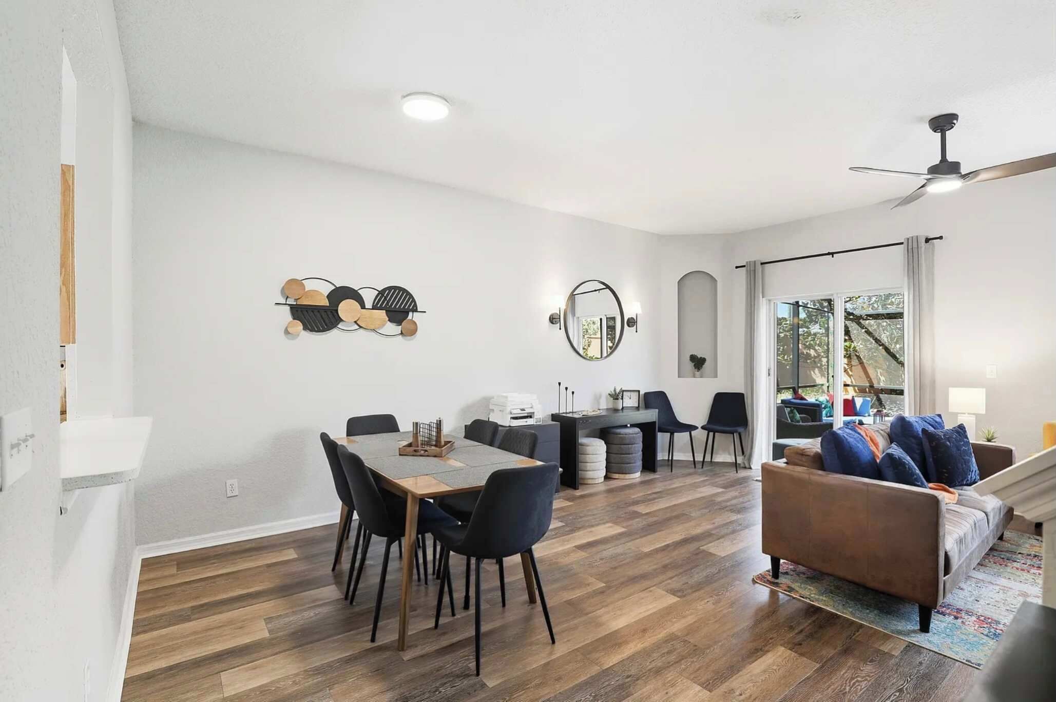 Un salon moderne comprenant un coin repas, un canapé et un ventilateur de plafond.