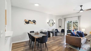 Een moderne woonkamer met een eethoek, een bank en een plafondventilator.