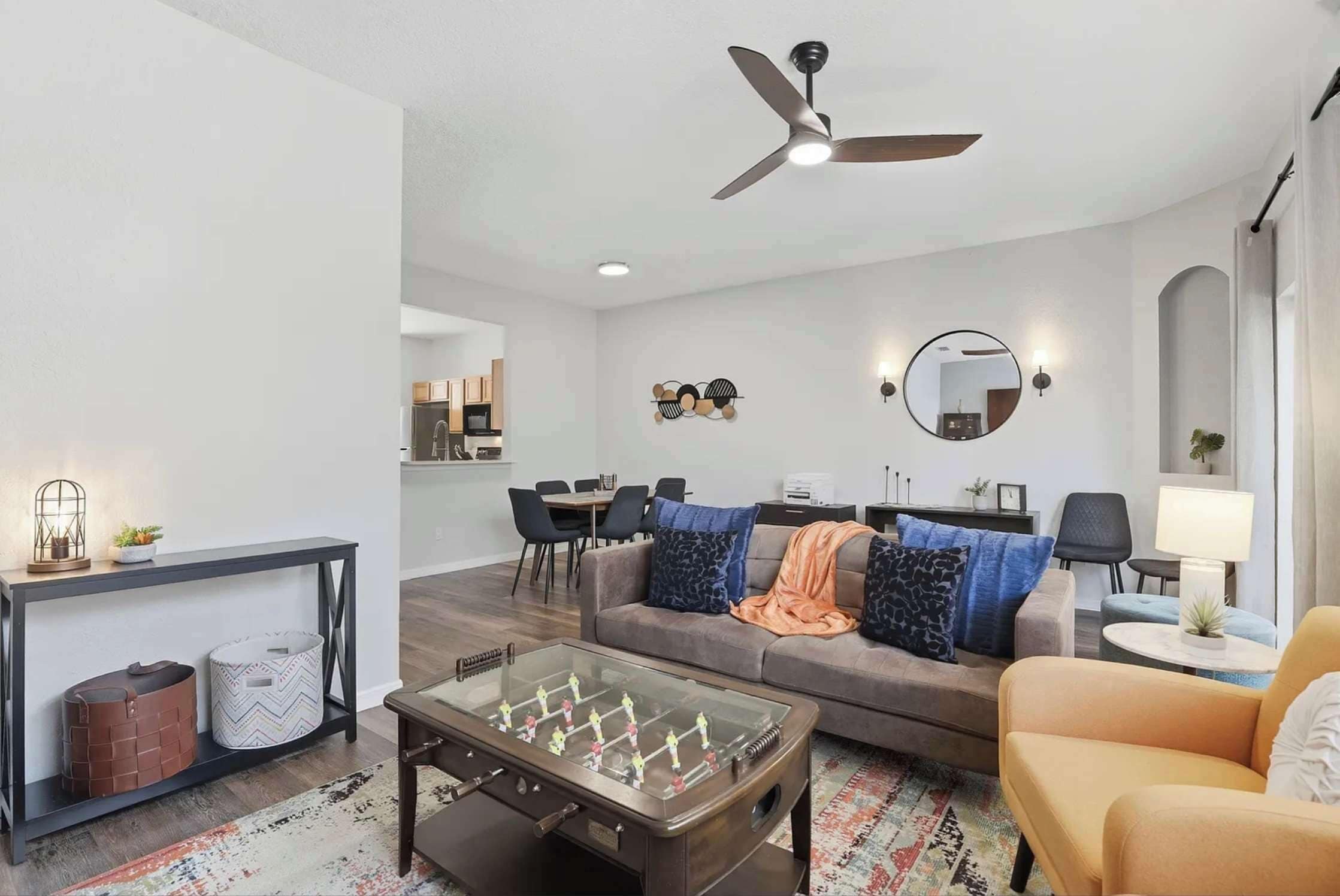 A modern living room with a sofa, coffee table, and a dining area in the background.