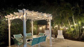 En uteplats med en pergola, ljusslingor och en pool.
