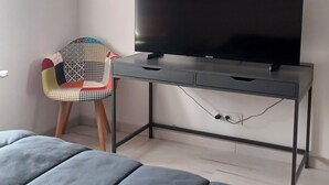 Un dormitorio moderno con una cama grande, un escritorio con televisor de pantalla plana y una silla colorida.