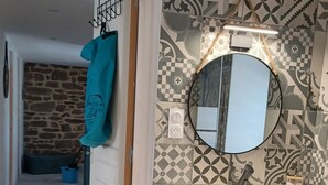 Un baño con lavamanos, espejo y azulejos estampados.