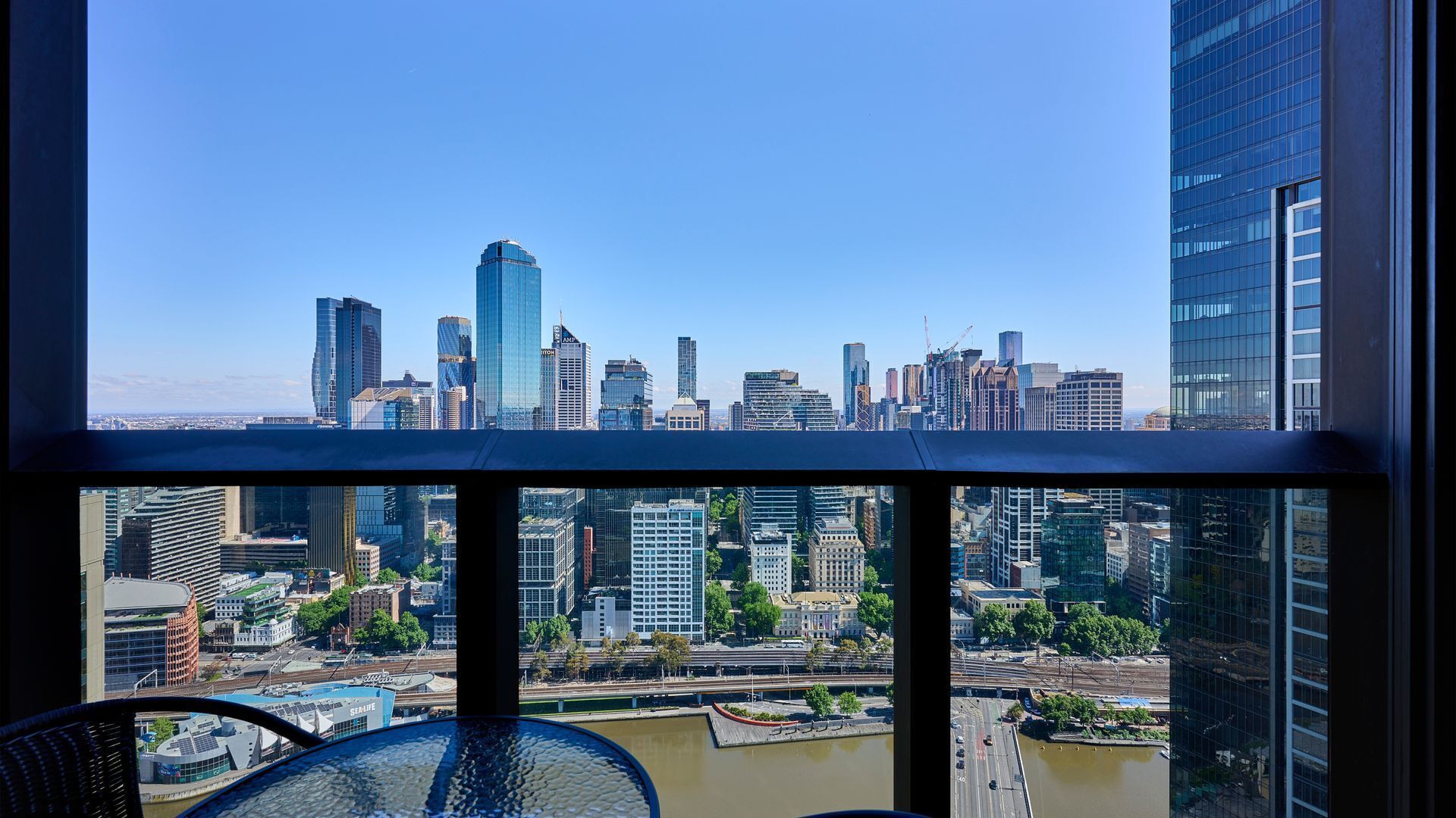 Une vue sur les gratte-ciel d’une ville, prise depuis un immeuble de grande hauteur, avec un ciel dégagé.