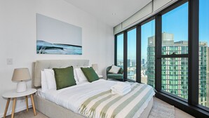 Ein modernes Hotelzimmer mit einem großen Bett, Blick auf die Stadt und einem Gemälde an der Wand.