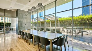 Ein moderner Konferenzraum mit großem Tisch und Stühlen, großen Fenstern mit Blick auf die Stadt sowie einer Decke mit eingelassener Beleuchtung.