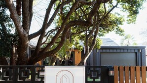 Zona cercada con un gran árbol, una valla de madera y un edificio con garaje.