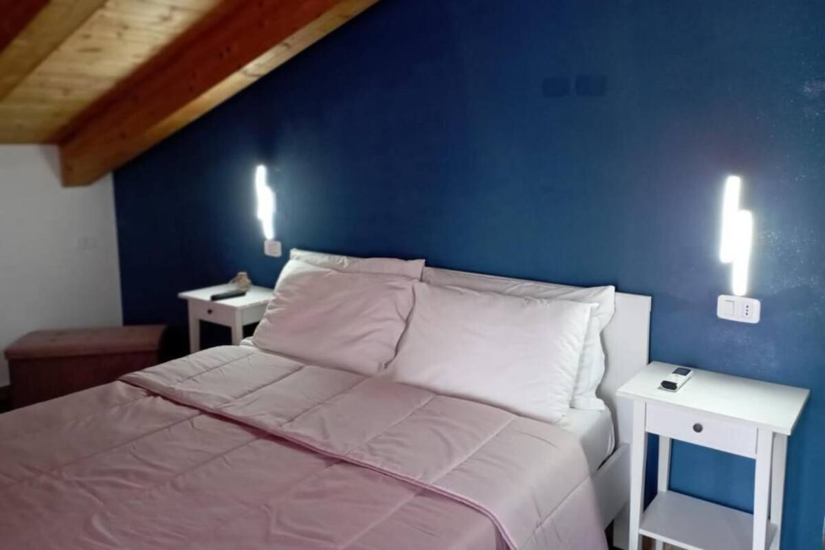 Une chambre à coucher avec un lit, des tables de chevet blanches et un plafond en bois.