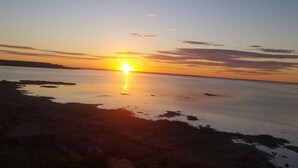 Un atardecer sobre un cuerpo de agua tranquilo con una orilla.