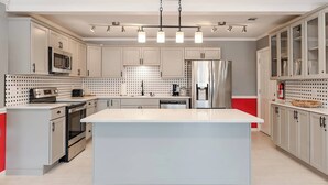 Une cuisine moderne avec des armoires blanches, des appareils en acier inoxydable et un îlot central.