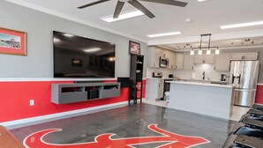Une chambre d’hôtel moderne dotée d’un grand téléviseur à écran plat, d’une kitchenette et d’une décoration aux couleurs rouge et gris.