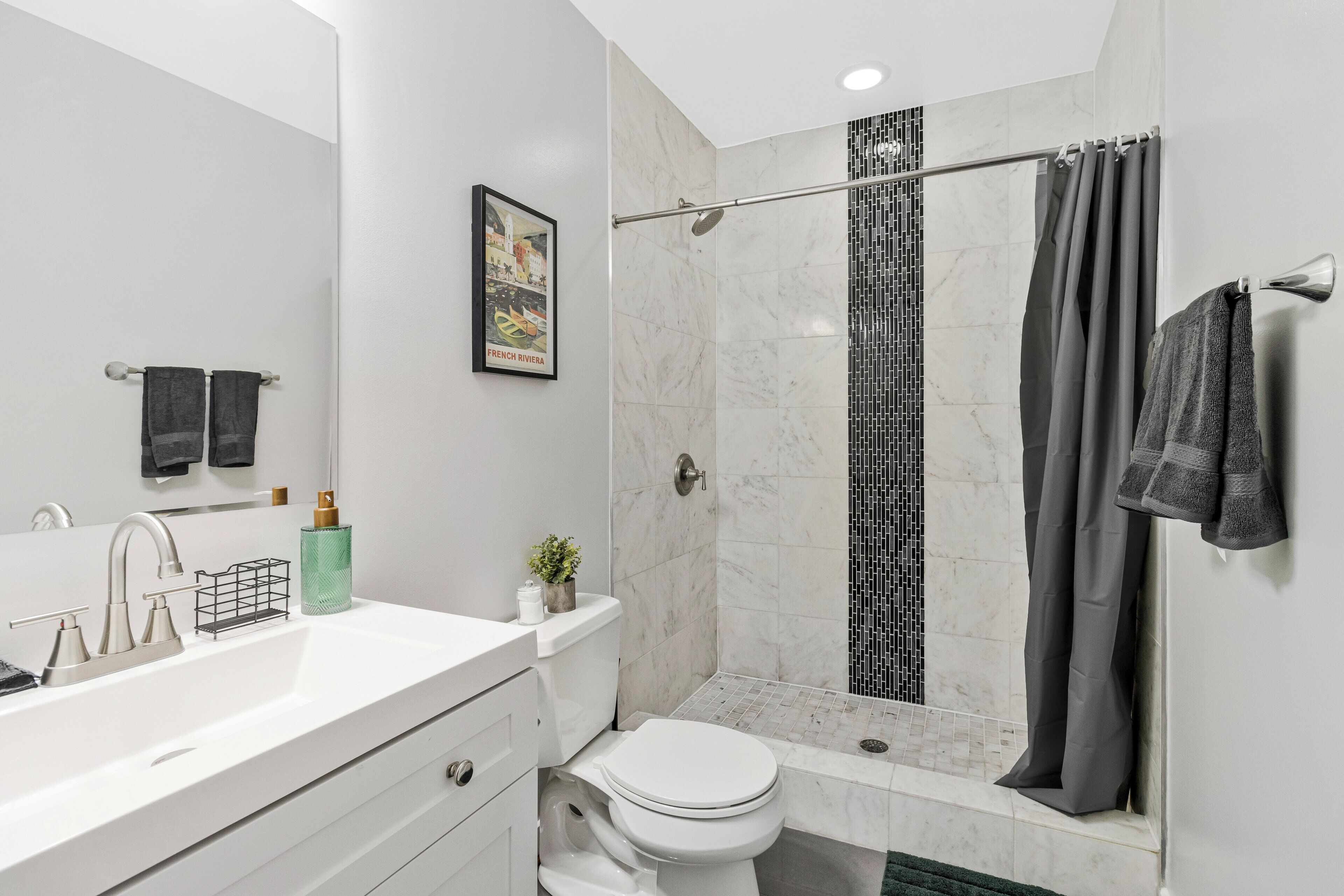 A modern bathroom with a white sink, a toilet, and a shower with a glass door.