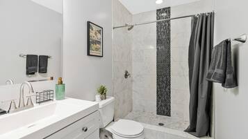 A modern bathroom with a white sink, a toilet, and a shower with a glass door.