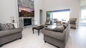 Ein modernes Wohnzimmer mit Kamin, grauen Sofas und einem großen Fenster.