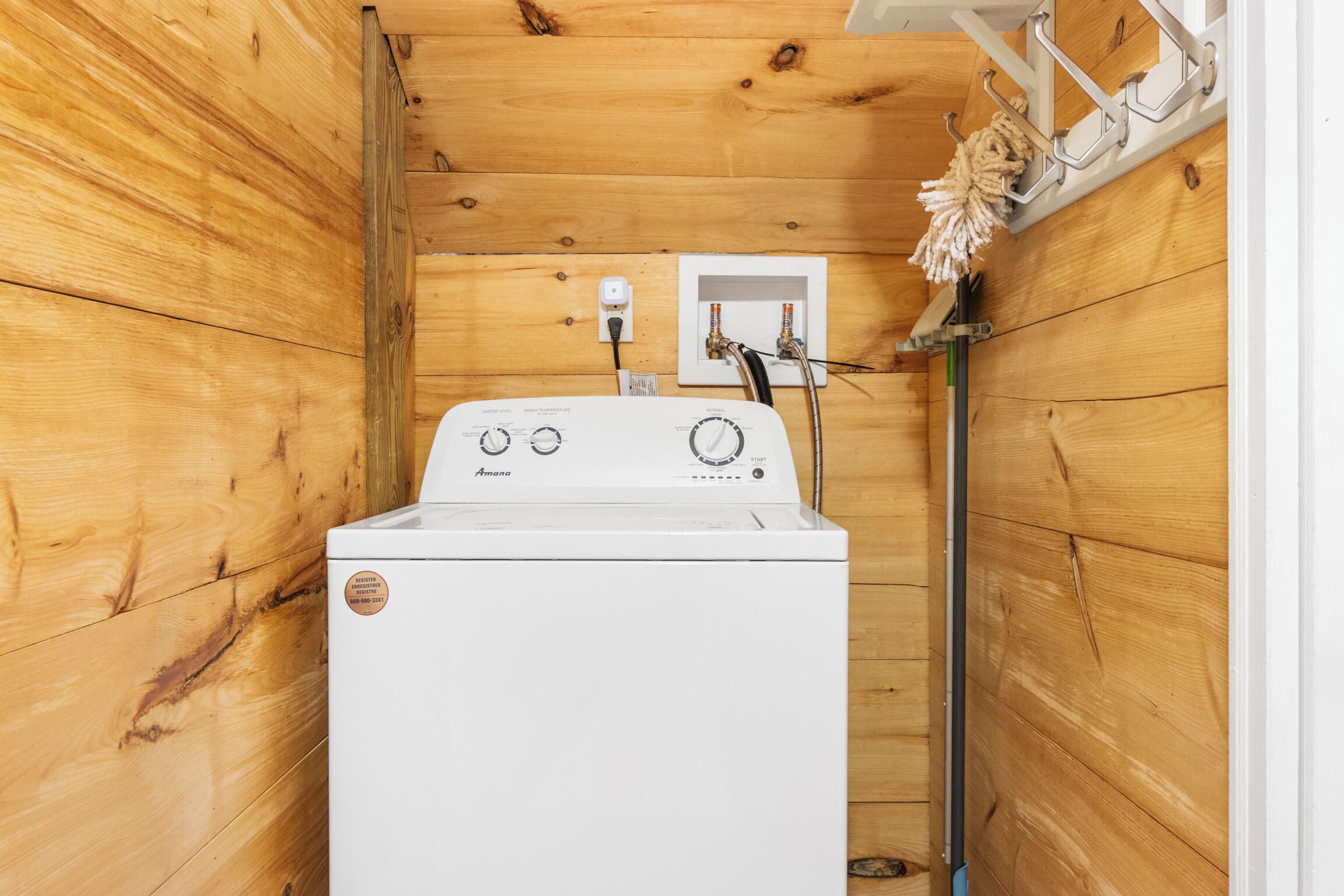 Un lave-linge et un sèche-linge compacts, de couleur blanche, installés dans une buanderie aux murs lambrés, avec un étendoir mural.