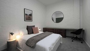 A bedroom with a bed, bedside lamp, a round mirror, a desk, and a chair. - Wow! Luxury inner-city two bedroom apartment (Dunedin)