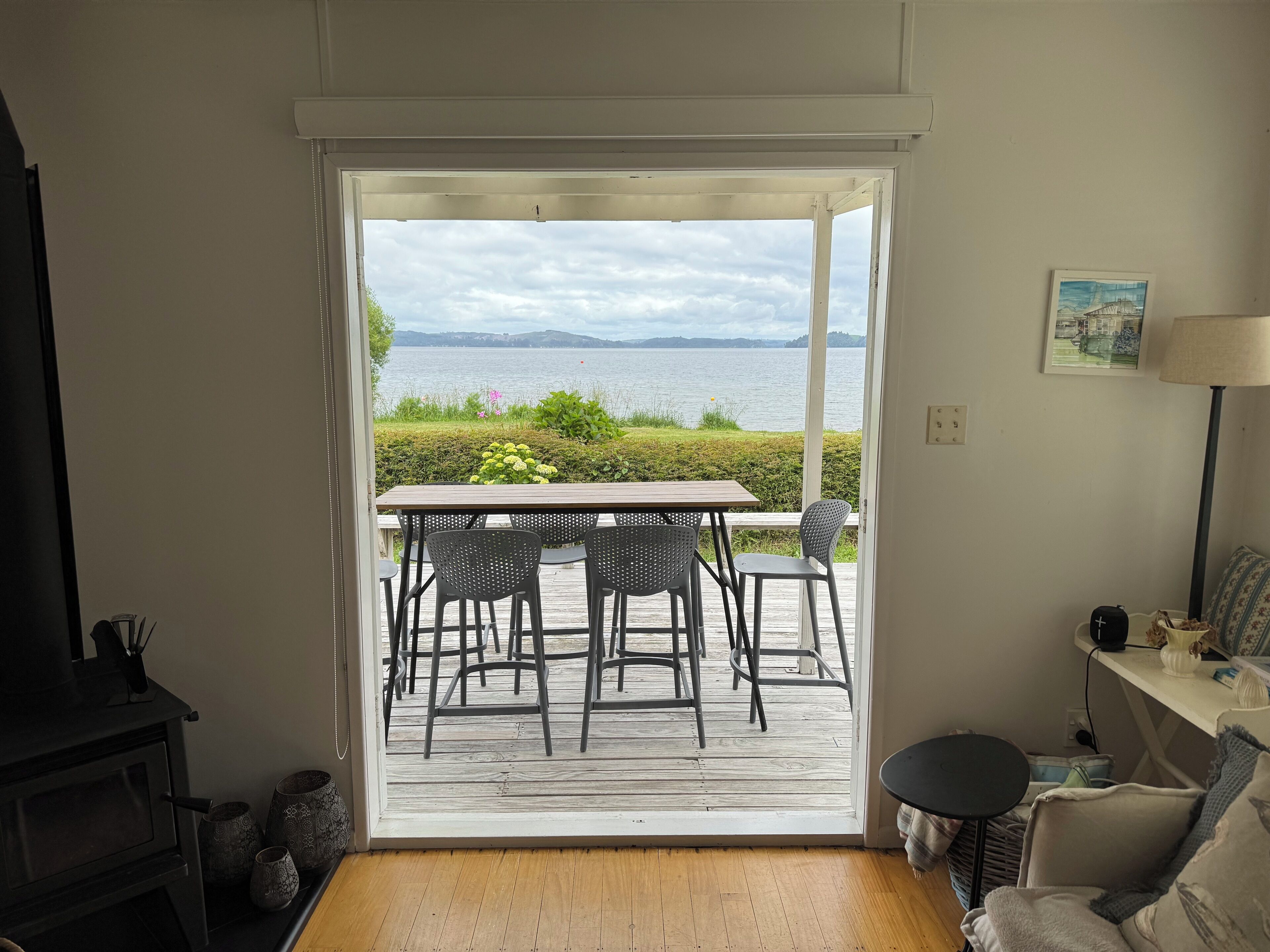 Una habitación con una mesa y sillas de madera frente a un ventanal que da a una masa de agua y montañas a la distancia.