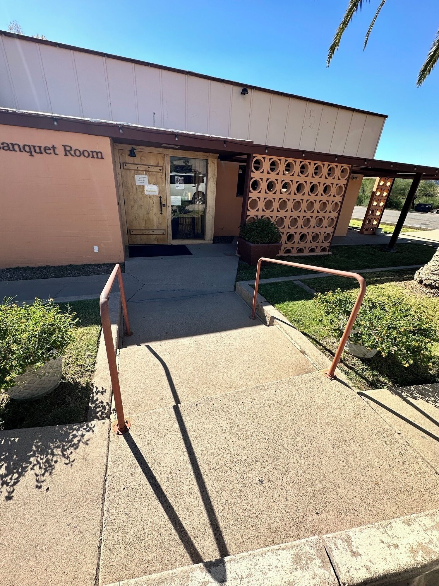 A building entrance with a sign reading "Banquet Room," a covered walkway, and a decorative wall with circular cutouts.