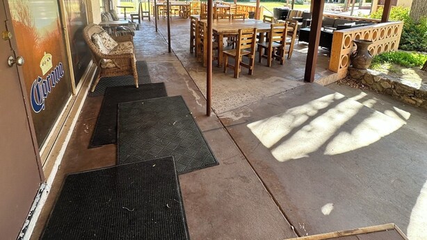 An outdoor patio area with wooden tables and chairs, a covered walkway, and a door labeled "Modelo". - General Kearny Inn (Kearny)