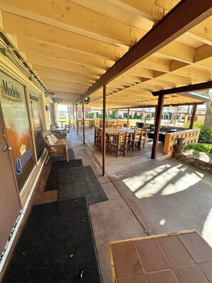 An outdoor patio area with wooden tables and chairs, a covered walkway, and a door labeled "Modelo". - General Kearny Inn (Kearny)