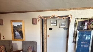 A room with a wooden floor, a gray armchair, a small table with a television, and a door with a sign. - General Kearny Inn (Kearny)