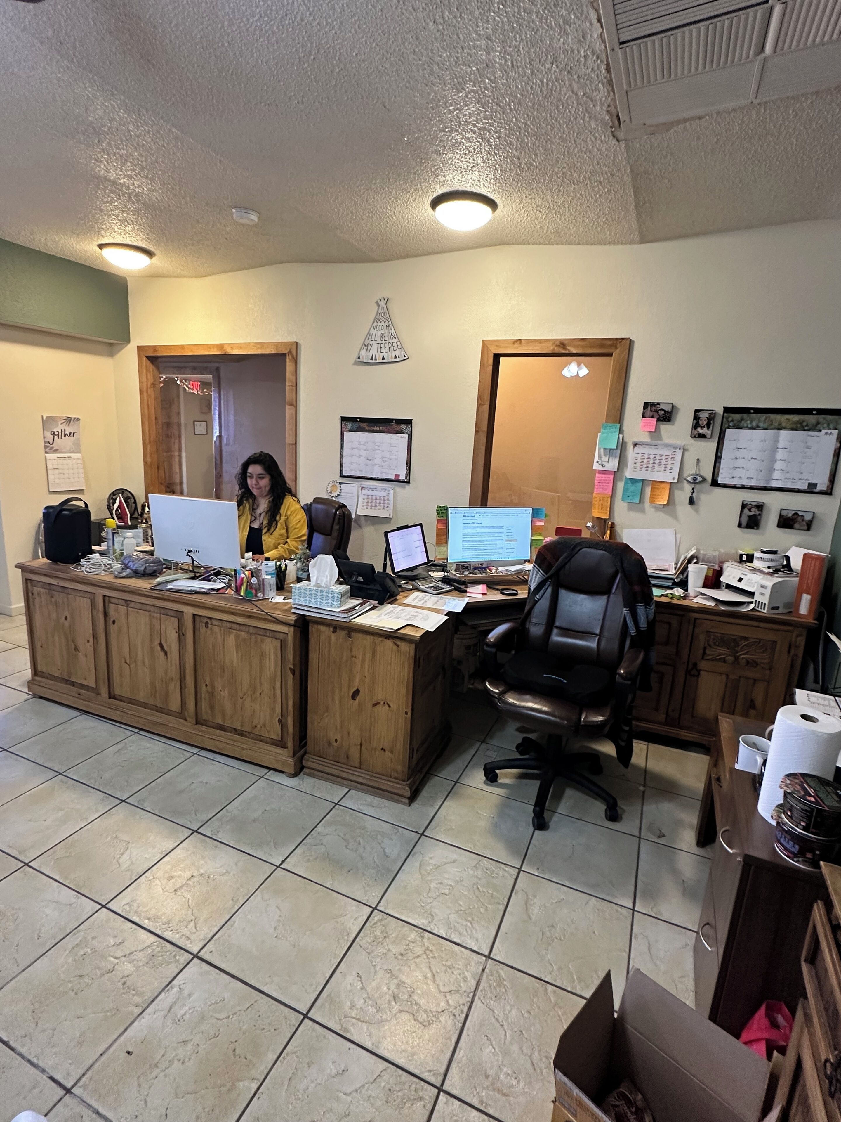 A reception desk with a computer, a chair, and various office supplies.