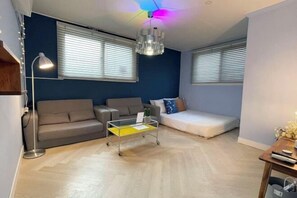 Un soggiorno con un divano, un tavolino, una lampada da terra e una ventola a soffitto.