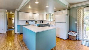 A modern kitchen with white cabinets, a central island, and a microwave. - Charming Fort Bragg Home with Ping-Pong & Fire Pit (Fort Bragg)