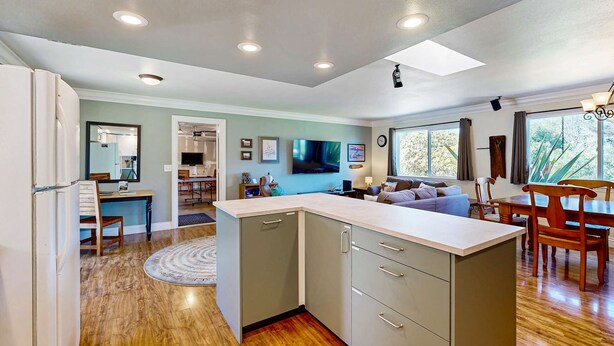 A modern kitchen with a central island, wooden flooring, and recessed ceiling lights. - Charming Fort Bragg Home with Ping-Pong & Fire Pit (Fort Bragg)