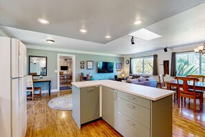 A modern kitchen with a central island, wooden flooring, and recessed ceiling lights. - Charming Fort Bragg Home with Ping-Pong & Fire Pit (Fort Bragg)