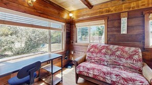A cozy cabin interior with a wooden interior, a sofa, a table, and a chair. - Eco-Conscious Home with Spacious Yard & EV Charger (Fort Bragg)