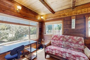 A cozy cabin interior with a wooden interior, a sofa, a table, and a chair. - Eco-Conscious Home with Spacious Yard & EV Charger (Fort Bragg)