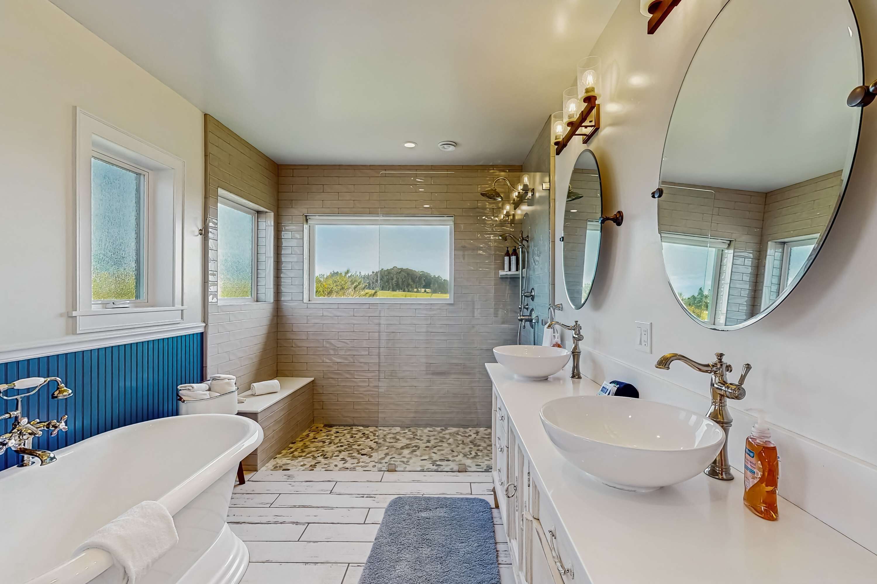 A modern bathroom with a freestanding bathtub, two sinks, and a large mirror.