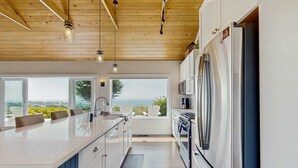 A modern kitchen with a large island, stainless steel appliances, and a view to the outdoors. - Albion Ridge Overlook - Luxury & Modern (Albion)