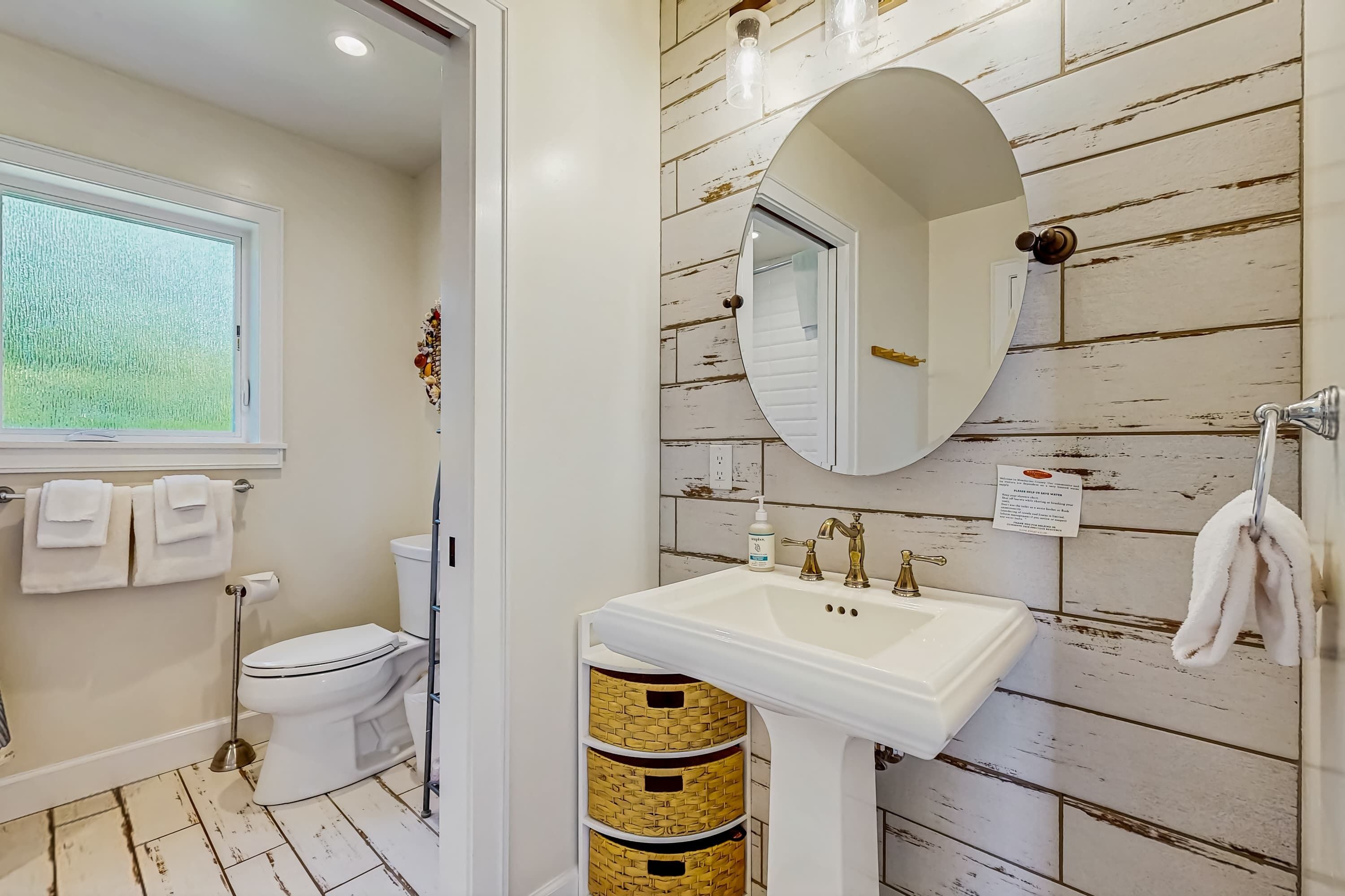 Baño con inodoro blanco, lavamanos y ventana.