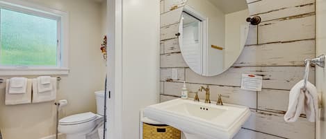 Baño con inodoro blanco, lavamanos y ventana.
