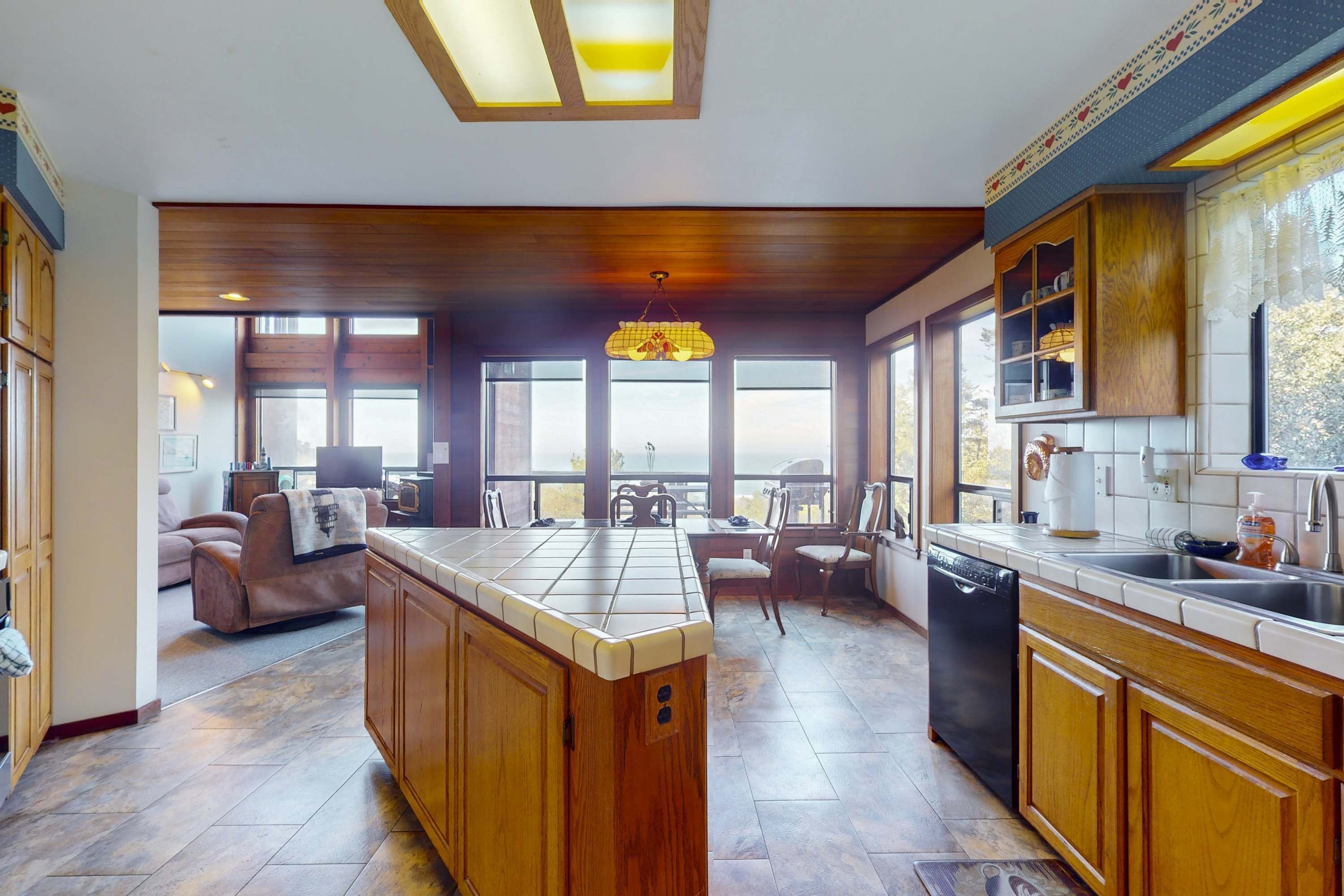 A spacious kitchen with wooden cabinets, a central island, and a dining area with chairs and a table.