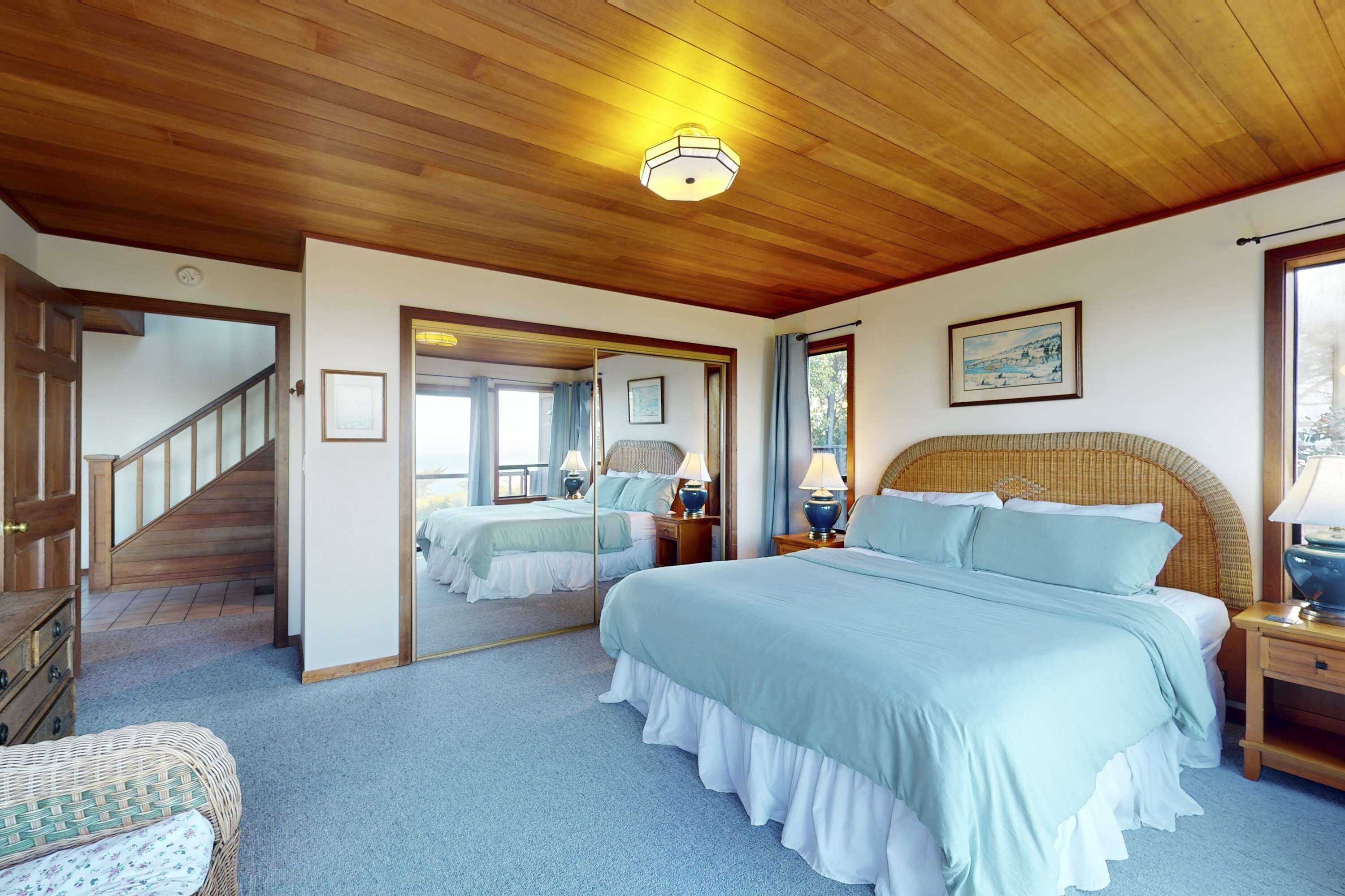 Un dormitorio con una cama grande, techo de madera, un espejo, una mesita de noche y una escalera.