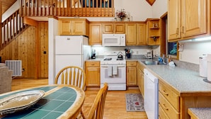 Une cuisine avec des meubles de rangement en bois, un four à micro-ondes, une cuisinière et un lave-vaisselle.